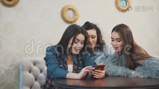 三个年轻的好女孩坐在咖啡馆里，花时间交流视频