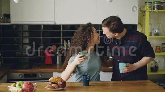 年轻快乐的白种人夫妇早上在现代厨房的爱会上一起吃早餐。 他们视频
