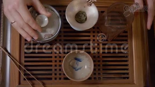 师傅用茶桌上的绿茶从盖湾的茶壶里倒热水视频