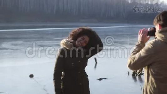 男人在冰冻的湖边给女人拍照视频