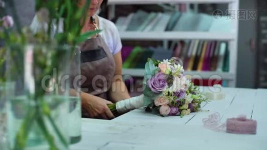 在花艺设计工作室，专业的花艺师用丝带布置婚礼花束视频