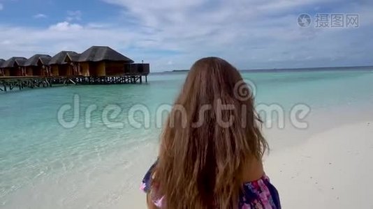 快乐的女人在马尔代夫的海边散步、微笑和旋转视频
