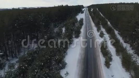 沥青路穿过松林.. 冬季，林道交通.. 冬季森林空中勘测视频