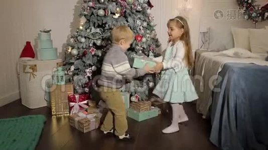 两个小朋友在圣诞树附近打开礼物。视频
