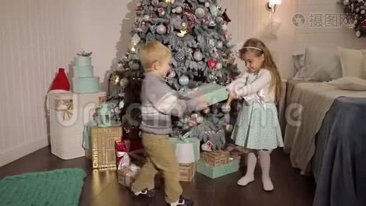 两个小朋友在圣诞树附近打开礼物。视频