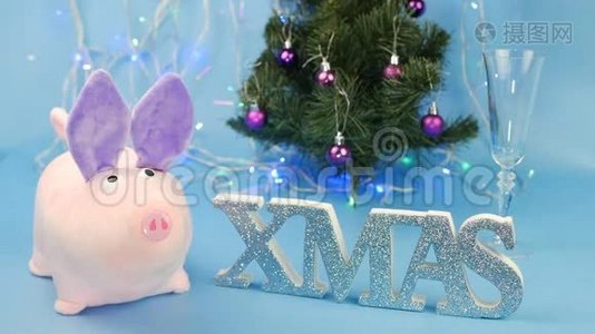 蓝色背景上的粉红色圣诞猪，背景上有一棵圣诞树和圣诞铭文，一个人倒着视频