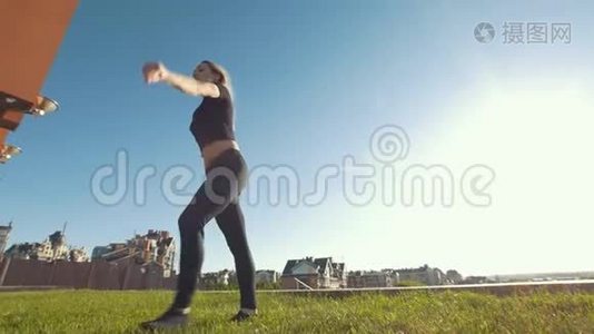 苗条的年轻女子在背景城市景观的草地上表演杂技跳跃。视频