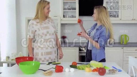 两个微笑的女朋友一起吃新鲜沙拉，在厨房里玩得开心视频