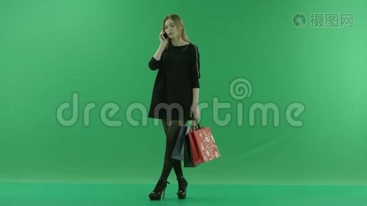 年轻健康的女士，带着购物袋，在手机上聊天，颜色关键绿色背景视频