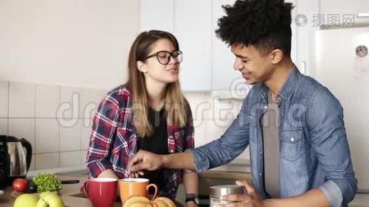 可爱的无辜的白种人女孩戴着时髦的眼镜亲吻她的穆拉托男友的脸颊。 吃午饭，花钱视频