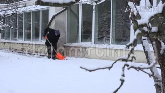 人用铲子清洁雪靠近房子的墙视频