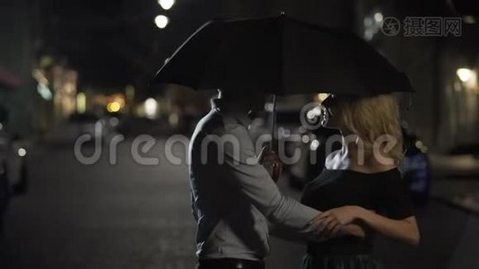 一对美丽的恋人在伞下拥抱，晚上约会，爱情故事视频