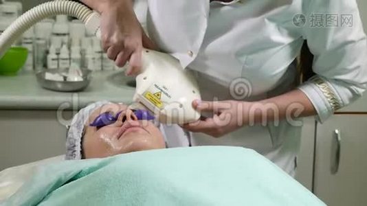 皮肤护理。一位戴眼镜的女士在美容院接受照片修复手术。美容师表演视频