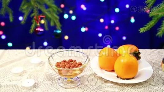 在新年背景下，餐桌上摆着蜂蜜和柿子`坚果，圣诞树上装饰着蛋蛋视频