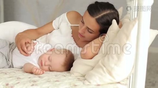 幸福的妈妈和她刚出生的婴儿躺在床上，她很佩服孩子。视频