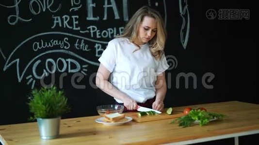 美丽的年轻女子用菜刀在木切割板上的圆片上切绿黄瓜，准备视频
