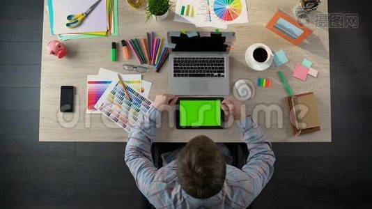 有创意的人用绿色屏幕浏览平板电脑，设计师观看照片视频