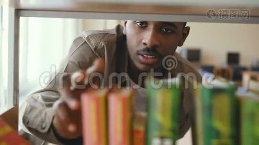 美国黑人严肃英俊的男学生正在大图书馆的书架上找课本，拿了一本书视频