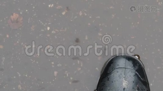 在水坑里穿着黑色橡胶靴的脚的俯视图视频
