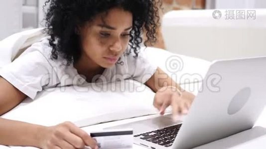 非裔美国妇女在床上网上购物，用信用卡支付视频