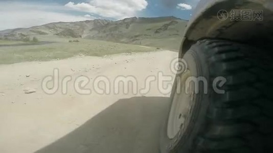 沿着山谷行驶的汽车车轮的景色。 越野车骑在乡村的高山公路上。 汽车旅行视频