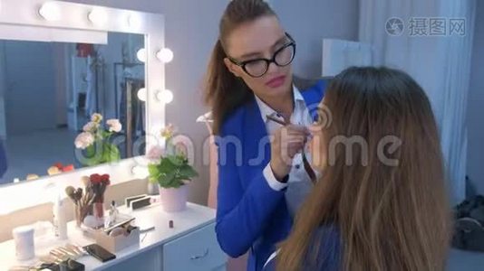 化妆师在美容院将口红用刷子涂在模特女孩的嘴唇上。视频