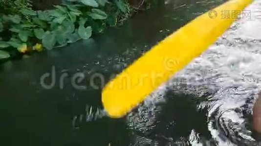 一个人坐在橡皮艇上，在河上划桨。视频