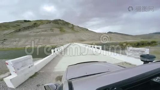 汽车旅行：SUV骑在一条河上的白桥上的高山公路上。 POV-车辆行驶的视角视频