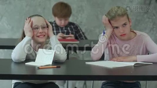 无聊的女孩坐在学校教室的桌子上，和同学讨论一些事情视频