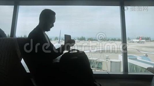 年轻人的剪影，他正在机场等待他的航班起飞。视频