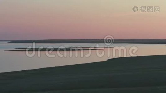 夕阳西下，美丽的粉红色天空，平静的水中的鸟岛视频