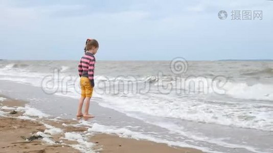 美丽的小女孩看着水边的海浪。 海上的弱风视频