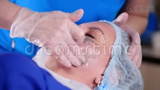 美容诊所。 年轻女性按摩师用奶油做专业的面部按摩。视频