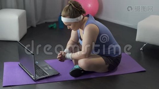胖乎乎的女孩紧张地从她的教练手提电脑上阅读锻炼和饮食计划视频
