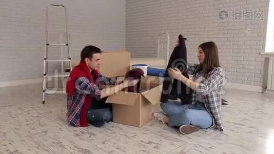 一对快乐的夫妇在他的新公寓里坐在地板上拆箱。视频