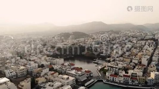 阴天时鸟瞰城市Agios Nikolaos.. 市中心的大型湖泊。 4K视频