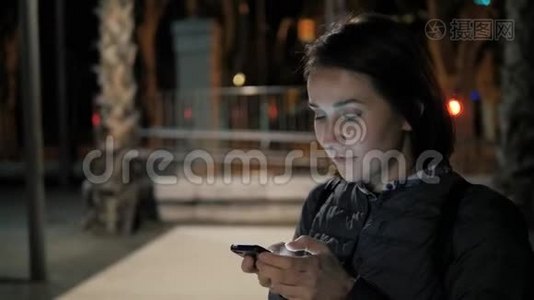 女孩使用智能手机语音识别，口述想法，语音拨号信息在晚上的街道，学生视频