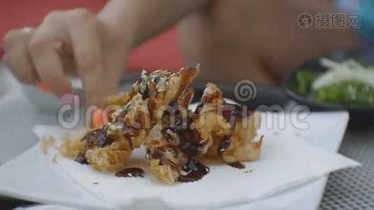 在日本餐馆的露天平台上，一位迷人的白种人年轻女士在咬和咀嚼天妇罗虾。视频