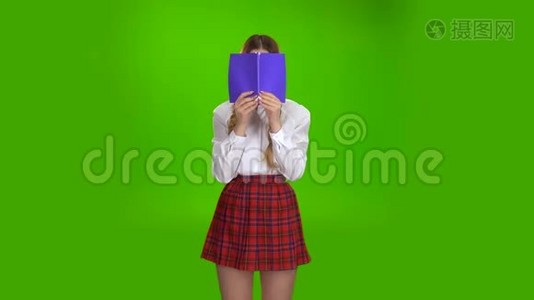 女学生用紫色的笔记本遮住了她的脸。 绿色屏幕视频