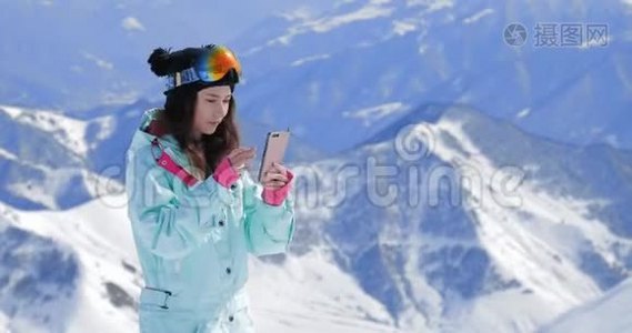 女滑雪者用她的智能手机，在山上拍摄冬天的大自然视频