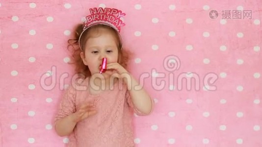恭喜你。 一个甜美的小女孩吹着派对的喇叭，微笑，玩得开心，笑着庆祝。 生日快乐。 特写视频