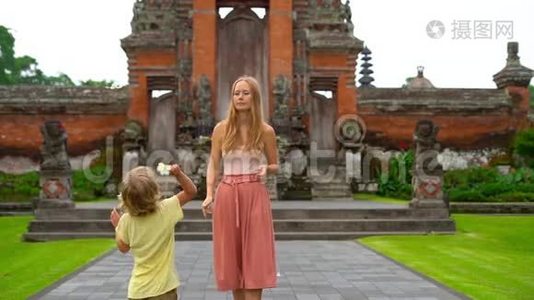 一名年轻女子和她的儿子在巴厘岛的塔曼·阿云寺周围行走时被慢镜头拍到视频