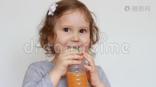 小可爱的女孩从瓶子里喝橘子饮料。 婴儿和新鲜果汁，冰沙，柠檬水，新鲜视频