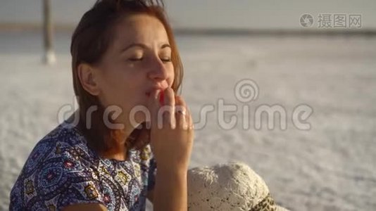 快乐的微笑女孩享受日落，吃西瓜，坐在盐上，特写视频