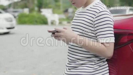 亚洲十几岁的男孩在路边玩手机游戏视频