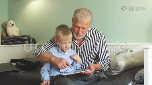 祖父和孙子坐在沙发上用数码平板电脑视频
