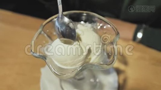 女孩用杯子里的勺子吃白色冰淇淋。 杯的特写..视频