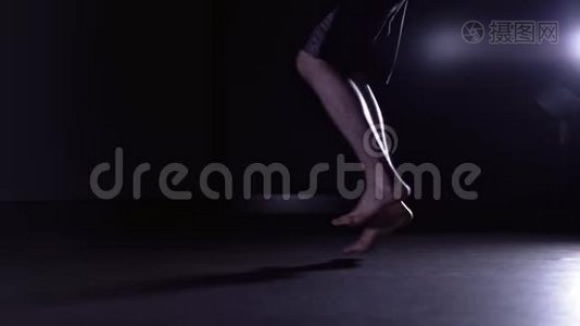 男人的腿在黑暗的健身房跳绳，侧视视频