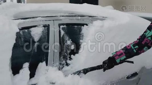 用刷子把她的车从冬天的雪中擦干净视频
