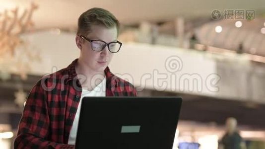 快乐的年轻嬉皮士戴着眼镜晚上在城里用笔记本电脑视频